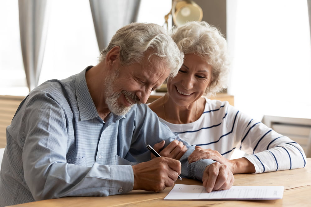Middle aged retired couple signing a contract