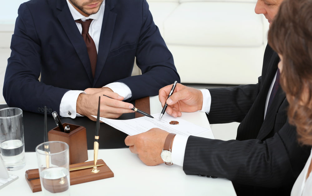 Two adults signing a contract with their lawyer