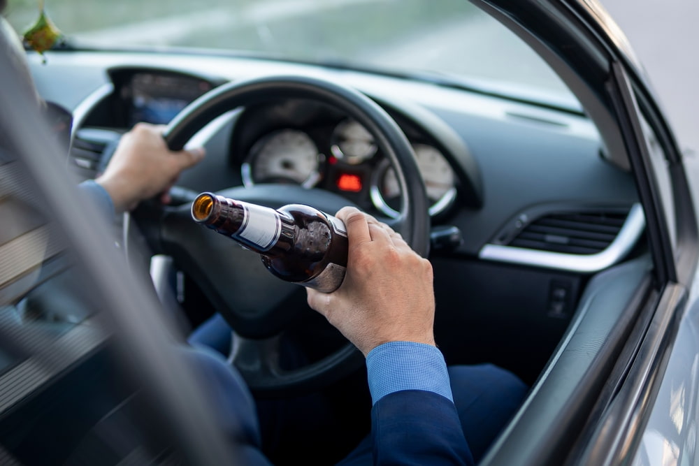 Man drinks a beer while driving